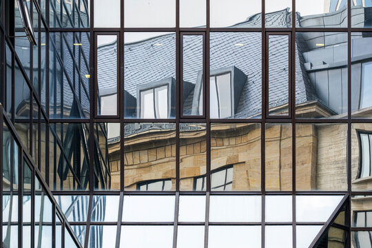 Glass windows reveal reflection across a corporate building facade, placing urban architecture and abstract geometry between roofline and courtyard light