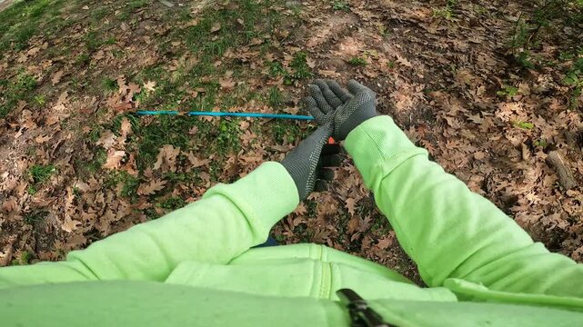 The process of raking fallen leaves with a rake. Worker rakes dry oak leaves in the park. Gardener removes leaves. First person view (POV). Spring or autumn garden cleaning. Work