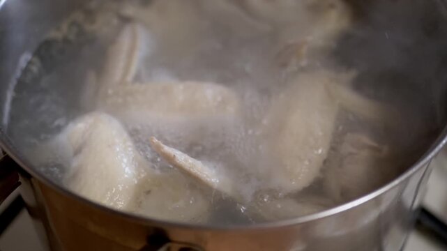 Close up, Fresh chicken wings are boiling in water, making them perfect for delicious savory dishes and wholesome home meals. The process of making chicken broth and soup.
