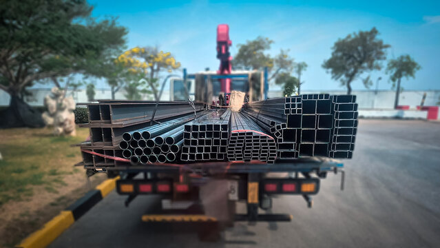 Workers preparing steel products for transportation on cargo truck in industrial yard, concept of logistics and construction materials delivery.