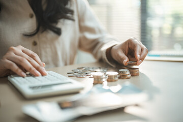 Woman counting coins beside calculator, showing emergency fund, savings cushion, personal finance,...