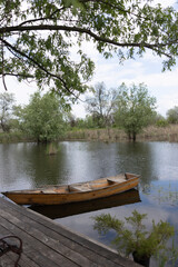 Fototapeta premium Wooden rowboat floating on calm lake water near pier