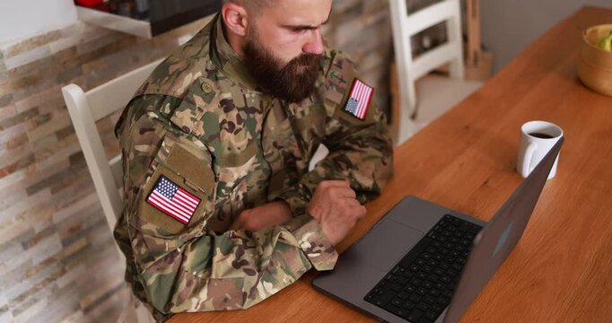 American soldier man in military uniform using computer laptop at home - Army, mission and technology concept