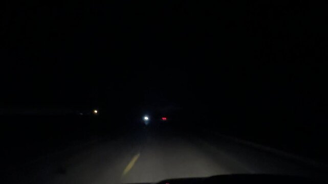 point of view footage capturing nighttime driving conditions on dark rural roadway with illuminated dashboard and low light transportation scene