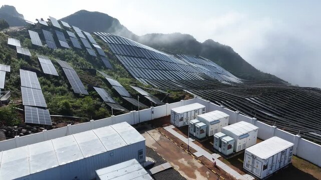Solar power plant with photovoltaic panels and energy storage containers on a mountain slope