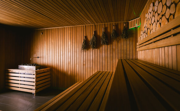 Traditional birch whisks hanging on a wooden wall in a rustic sauna interior