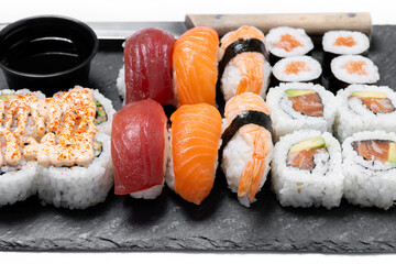 Assorted Sushi Selection and soy sauce on slate tray isolated on white background © chandlervid85