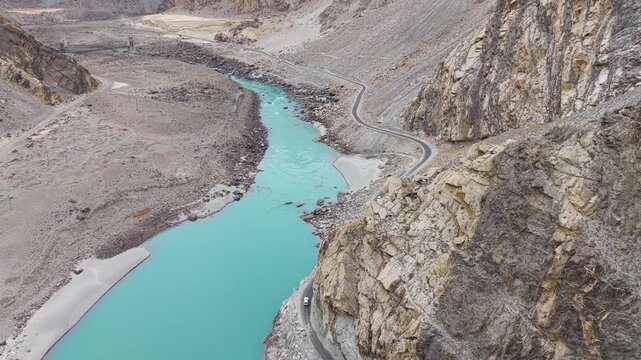 Cinematic nadir drone tracking shot of a car on the winding KKH mountain road.