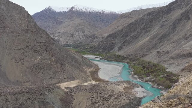 Cinematic nadir drone shot of scattered boulders and silty river channels in Skardu, Pakistan.