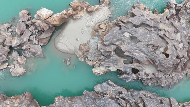 Cinematic nadir drone shot of a winding river through a rocky desert valley in Pakistan.