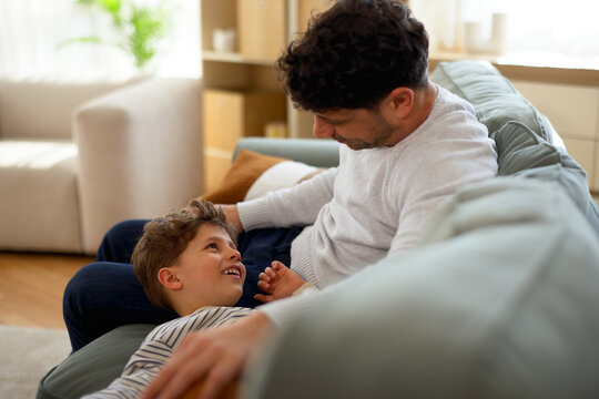 Father and son sharing affectionate moment on living room sofa
