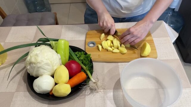 Cooking vegetable preparations, Chef slices vegetables peacefully, Person expertly chopping vegetables beside bowl, Individual skillfully preparing assorted vegetables at kitchen counter