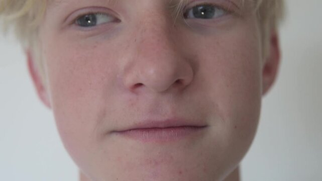 Close-up portrait of a teenage boy smiling with dental braces. Cropped face focusing on eyes, nose, mouth and orthodontic treatment, showing a natural adolescent smile and dental care concept