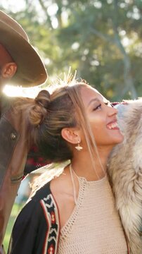 Laugh, hug and friends at festival, outdoor and hippie fashion at social gathering for bonding. Excited, embrace and funny people in nature with gems, flare and huddle at reunion together for fun