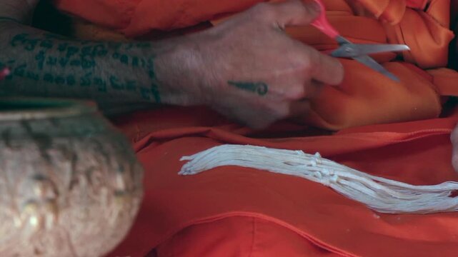 Thai Buddhist Monk Tying Blessing Bracelet on Worshipper's Wrist