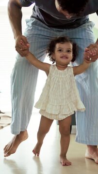 First steps, milestone and walking in home with father, toddler and development or growth. Balance, learning or support with dad, man and excited child in bedroom for motor skills or movement