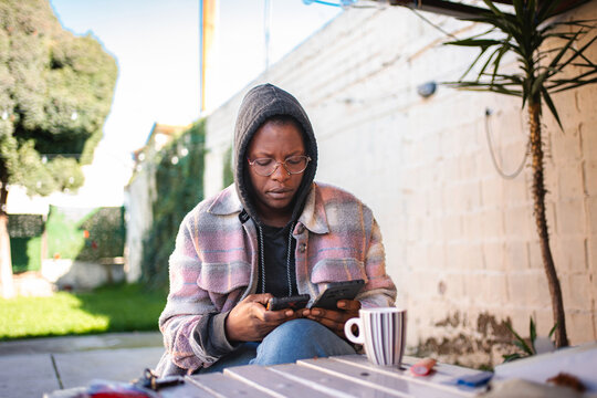 Woman multitasking with two smartphones and coffee outdoors
