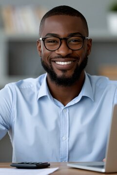 Smiling man with glasses using calculator and laptop for finance professional headshot and business profile portrait
