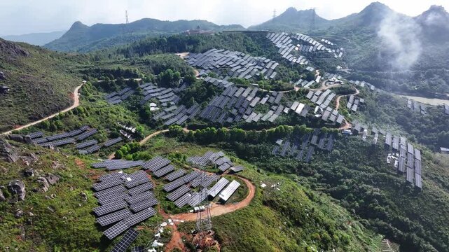 Aerial view of mountain photovoltaic power station with solar panel arrays and green landscape