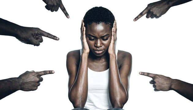 A person sits, head down, hands over ears, surrounded by accusing fingers pointing