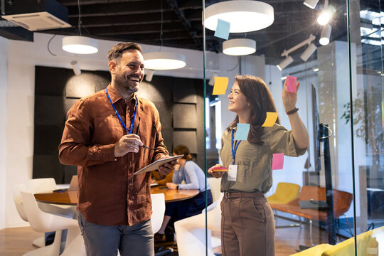 Business colleagues collaborating on creative ideas using sticky notes during a brainstorming session in a modern office