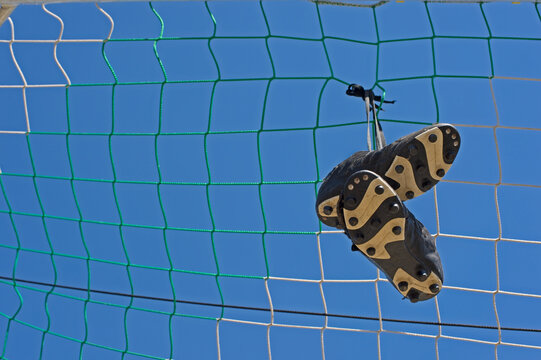Germany, Bavaria, Munich, football shoes hanging in football net
