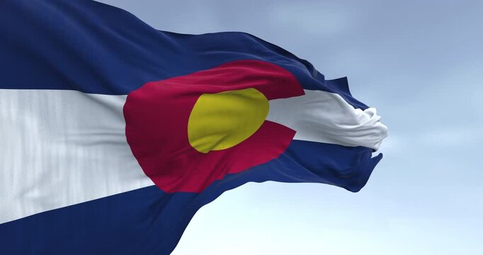 Close-up of Colorado state flag waving in the wind on a clear day. Three blue, white, and blue stripes. Red C with gold disk on top. Seamless 3d render animation. Slow motion loop. Selective focus