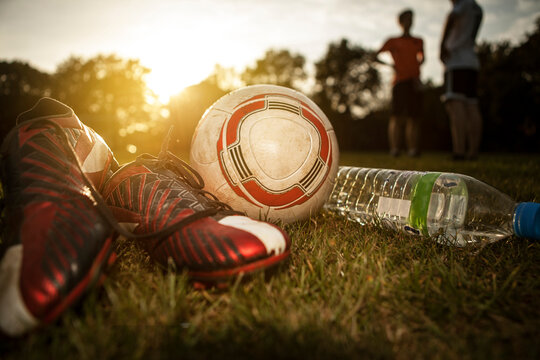 Soccer shoes, ball and bottleof water on soccer pitch