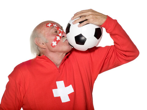 Senior man with Swiss flag painted on face and kissing football