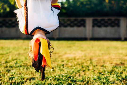 Boy in German football shirt, hanging upside down with face covered by German flag