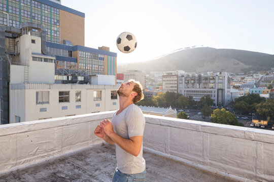 Young man playing football on rooftop terrace