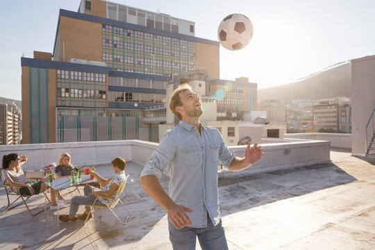 Friends meeting on rooftop terrace in summer, playing football