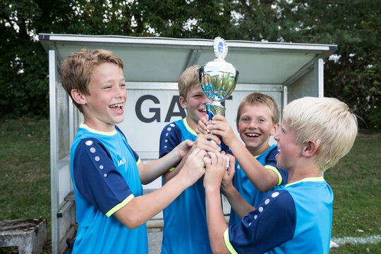 Young football players cheering with cup