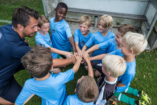 Coach and young football players huddling