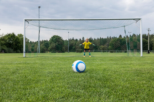 Young football goalkeeper with ball on football ground