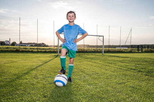 Portrait of confident young football player with ball on football ground