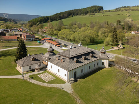 Aerial view of Kastiel Kubinyi manor house with its traditional shingle roofs and surrounding green parkland under a clear blue sky in Vysny Kubin, Zilinsky kraj, Slovakia.