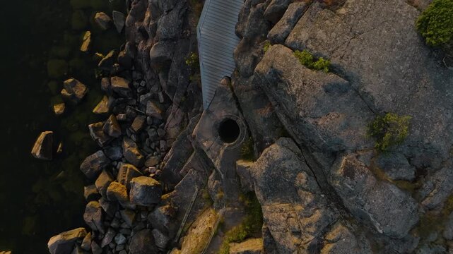 Birdseye drone shot descending above a giant's kettle geological feature in Hanko