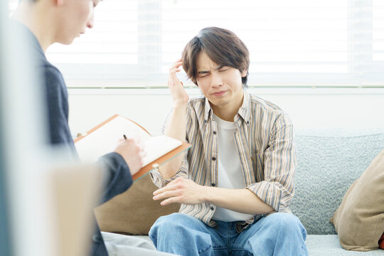 ソファに座ってカウンセリングを受ける若い日本人男性