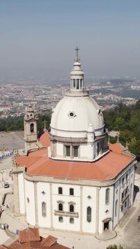 Vertical aerial panning shot capturing monumental architecture of Sameiro Sanctuary and scenic cityscape in Braga, Portugal.