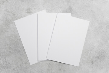 Three blank white sheets of paper arranged on a textured gray surface, ideal for design mockups or presentations © nikavera