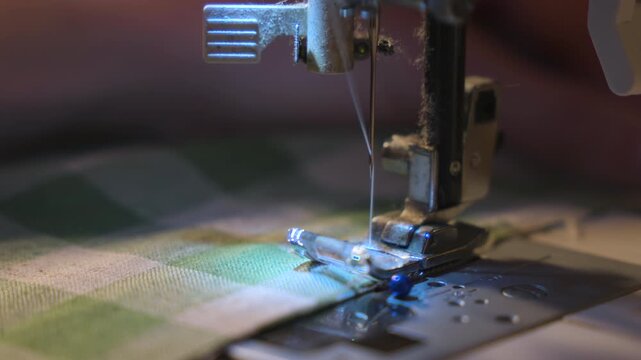 Sewing machine making home made craft. Close-up of green and white fabric in slow motion.