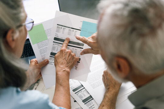 Senior couple analyzes utility bills and bank statements at home together