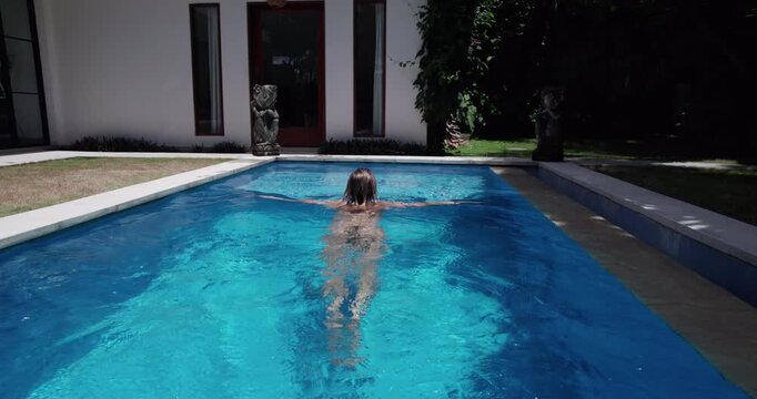 Woman swims in pool in Bali while enjoying workation as a global nomad