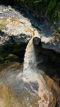 Spectacular drone flyover of Kapas Biru waterfall Java &ndash; Amazing tropical rainforest valley with misty morning fog and majestic red cliff walls, premium Indonesia tourism advertising background