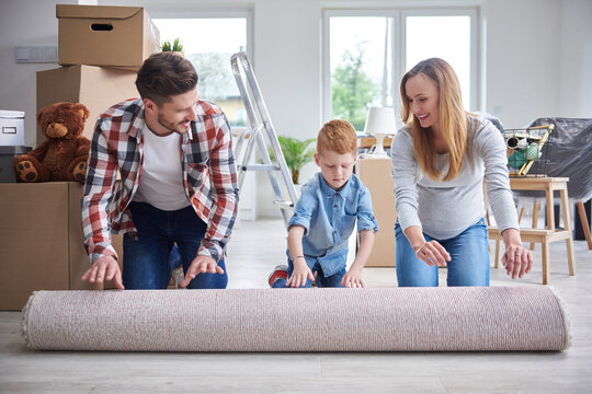 Family unrolling a carpet in new flat