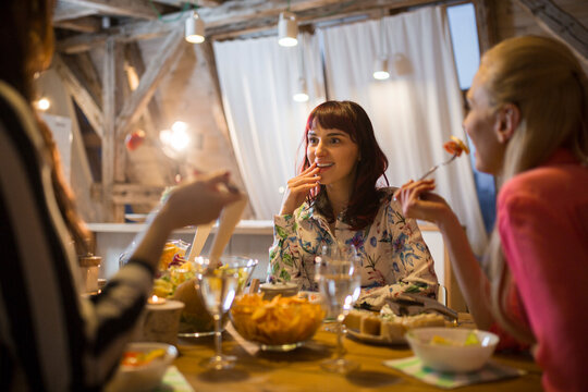 Happy female friends having dinner at home together