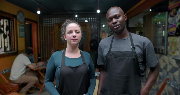 Serious small business caf&eacute; staff standing side by side inside neighborhood restaurant expressing focus responsibility mutual respect commitment teamwork daily work reality