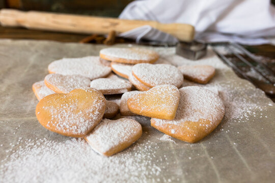 Heart-shaped shortbreads sprinkled with icing sugar on parchment paper