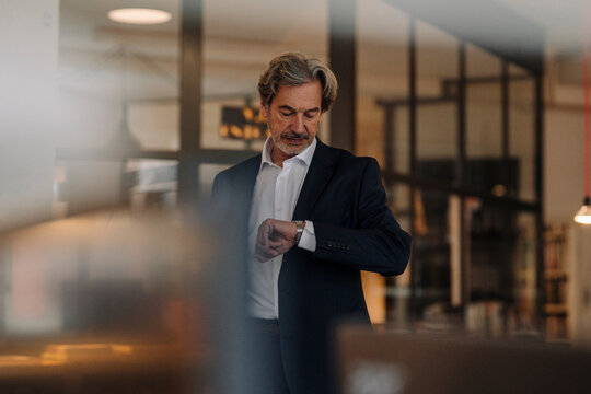 Senior businessman checking the time in office